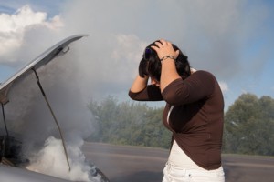 Woman looking at smoking car engine